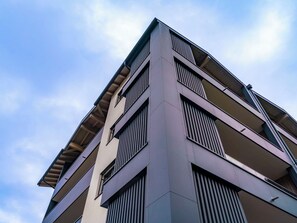 Ein mehrstöckiges Gebäude mit modernem architektonischen Design, ausgestattet mit Balkonen und großen Fenstern.
