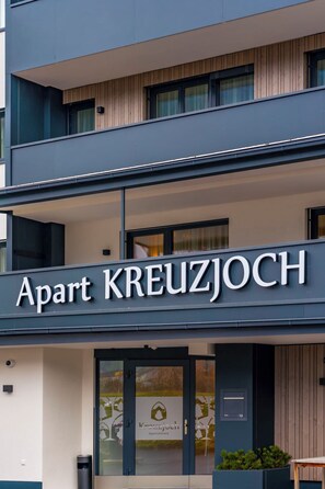 En byggnad med en skylt där det står ”Apart KREUZJOCH” och en logotyp för ”Kreuzjoch Apartments”.