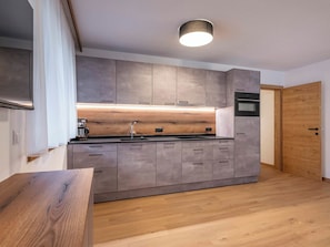Eine moderne Küche mit grauen Schränken, einer Holz Arbeitsplatte und einem eingebauten Backofen.