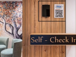 Ein Selbstcheck-in-Bereich mit Holzverkleidung, einem QR-Code und einem Schild.