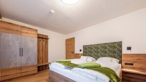 Une chambre à coucher avec un lit en bois, une armoire et une tête de lit ornée d’un motif floral.
