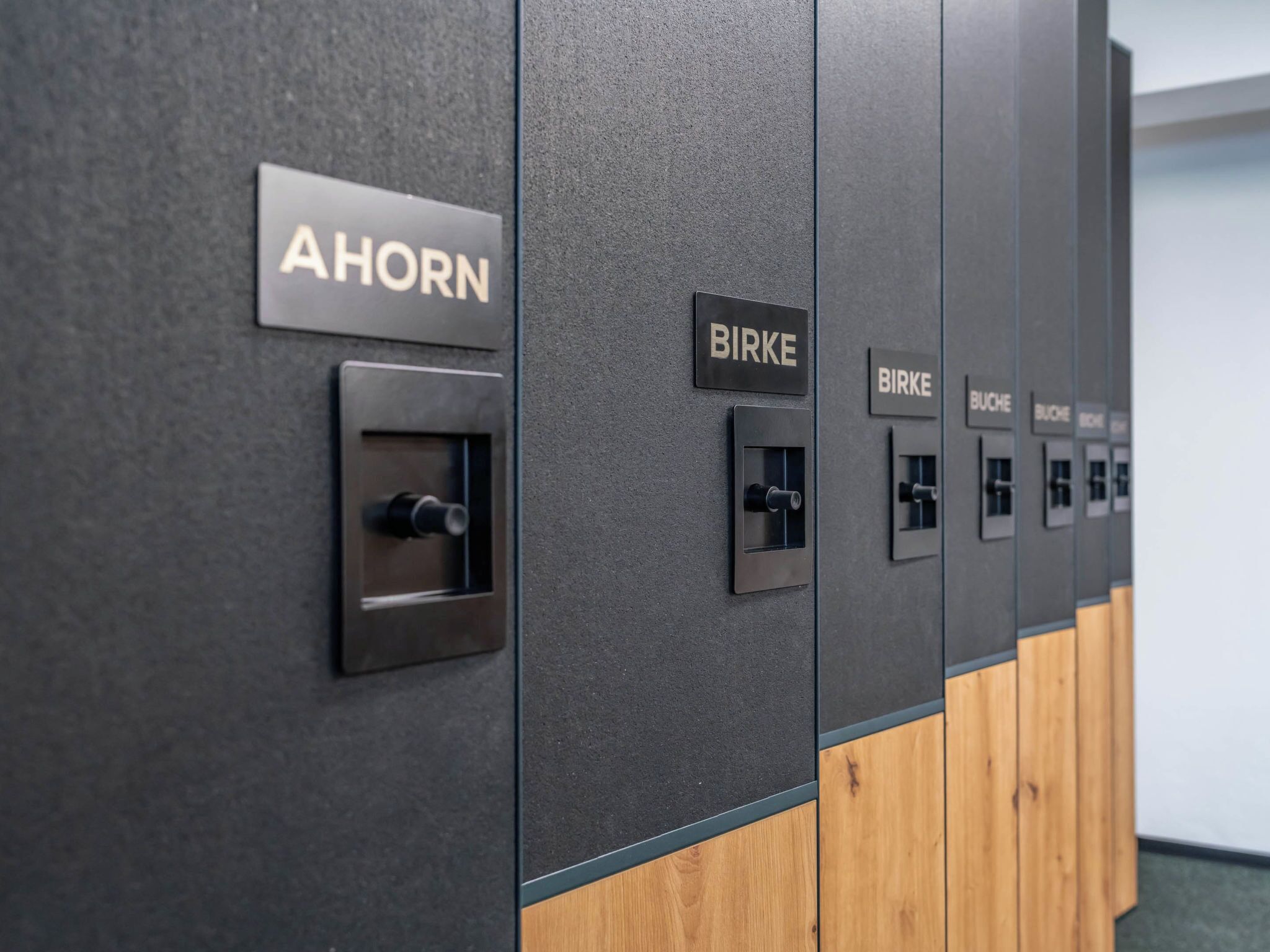 Eine Reihe von Schließfächern mit den Schildern 'AHORN' und 'BIRKE', welche Zimmernummern angeben.