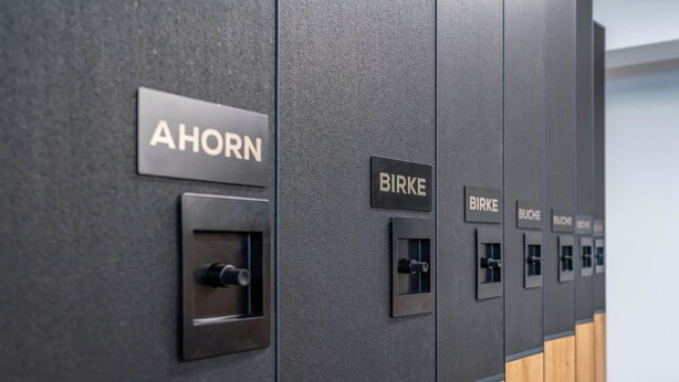 Une rangée de casiers portant les étiquettes « AHORN » et « BIRKE », qui indiquent les numéros des salles.