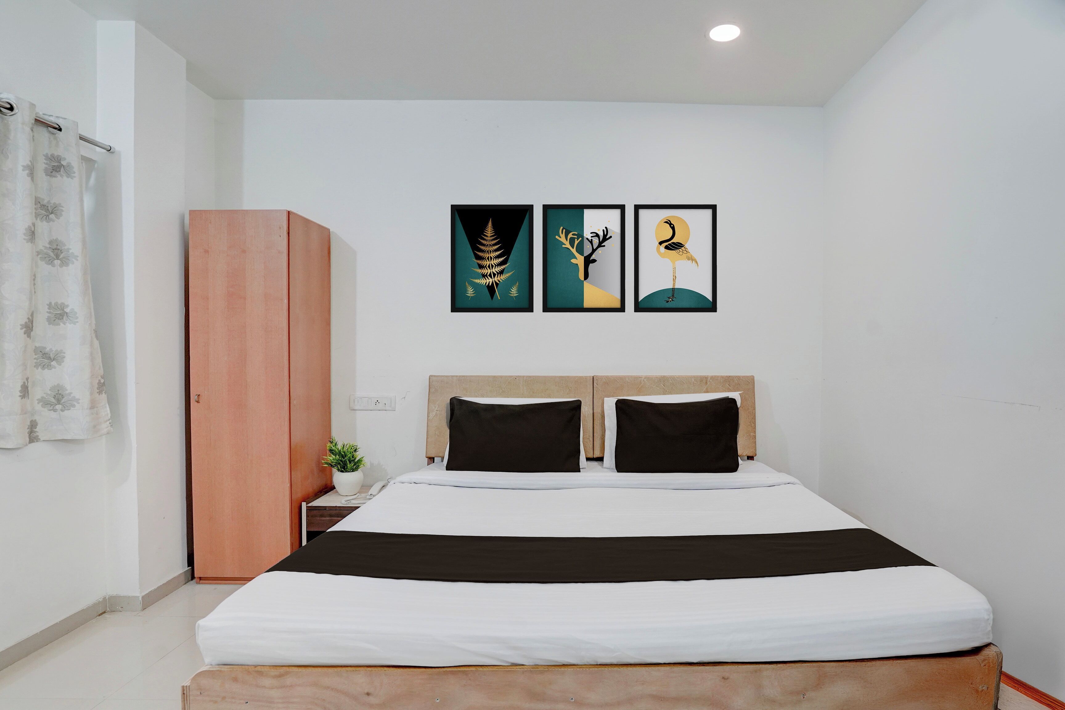 Un dormitorio con una cama, un armario y tres obras de arte enmarcadas en la pared.
