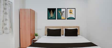 A bedroom with a bed, a wardrobe, and three framed artworks on the wall.