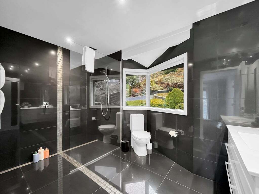 Ein modernes Badezimmer mit Duschkabine aus Glas, Toilette und Waschbecken.