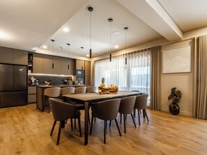 A modern kitchen with a dining area, wooden flooring, and a large window with curtains. - Vacation home Alfa by Interhome (Lovinac)