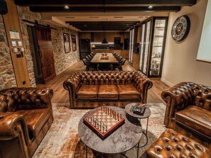 A spacious lounge area with leather sofas, a chess table, and a dining area with a long table and chairs. - Vacation home Alfa by Interhome (Lovinac)