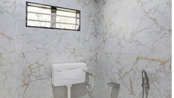 A bathroom with a toilet, a shower, and a window.