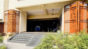 A building entrance with a set of stairs leading up to a door, a ceiling fan, and a gated entrance with decorative metalwork.