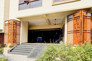 A building entrance with a set of stairs leading up to a door, a ceiling fan, and a gated entrance with decorative metalwork.