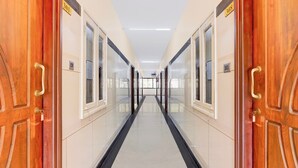 A corridor with doors marked with numbers, a tiled floor, and a ceiling with lights.