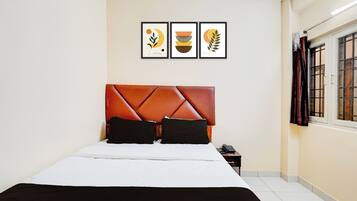 A hotel room with a bed, a nightstand, a telephone, and three framed artworks on the wall.