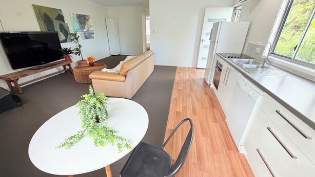 En moderne stue med sofa, fjernsyn og spisebord med en plante.