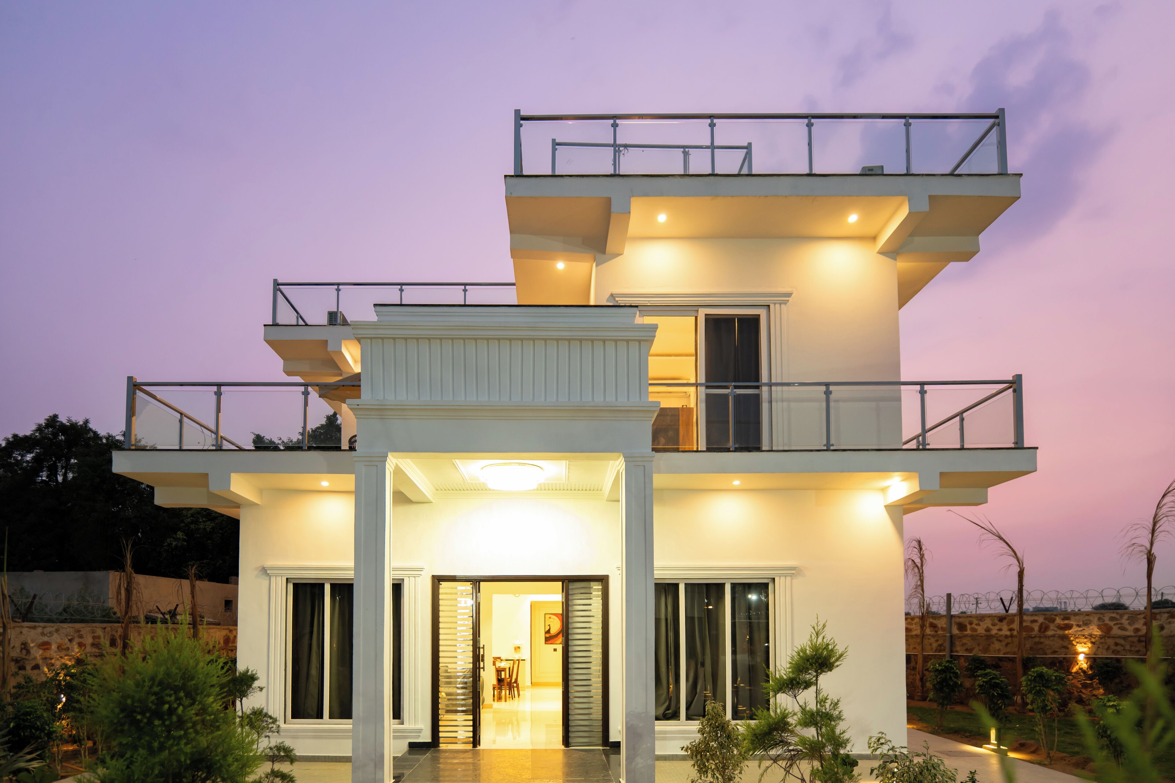 A modern two-story building with a balcony, large windows, and a well-lit entrance.