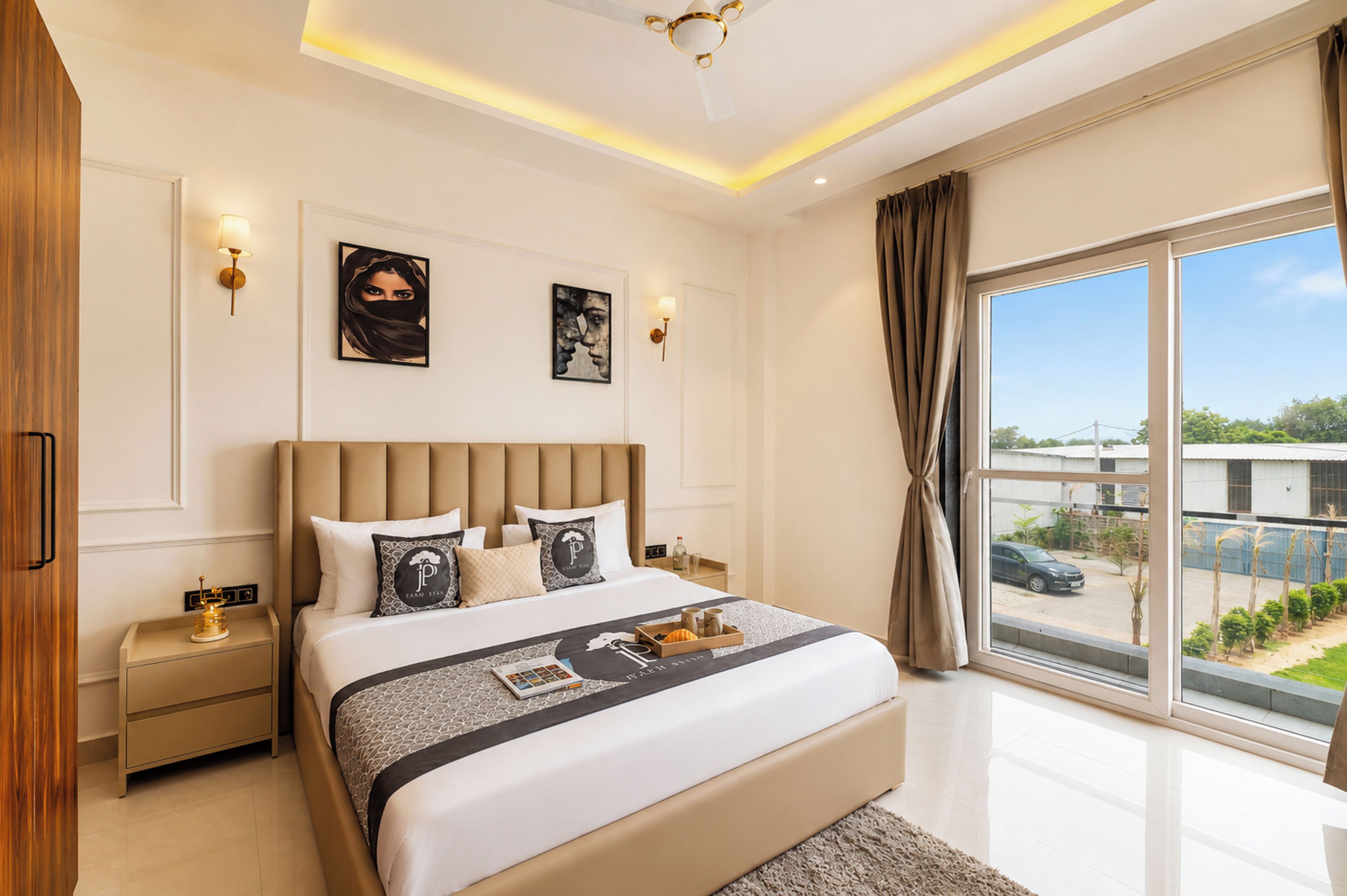 Une chambre moderne avec un grand lit, des tables de chevet, des œuvres d’art murales et une vue sur l’extérieur.