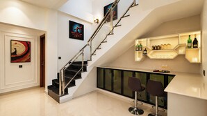 A modern interior with a staircase, a bar area, and artwork on the walls. - ELIVAAS JP Farm Stay 5BHK Villa With Bar (Baghanki)