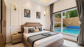 A bedroom with a large bed, a nightstand, a wall-mounted lamp, and a window with a view of a swimming pool.