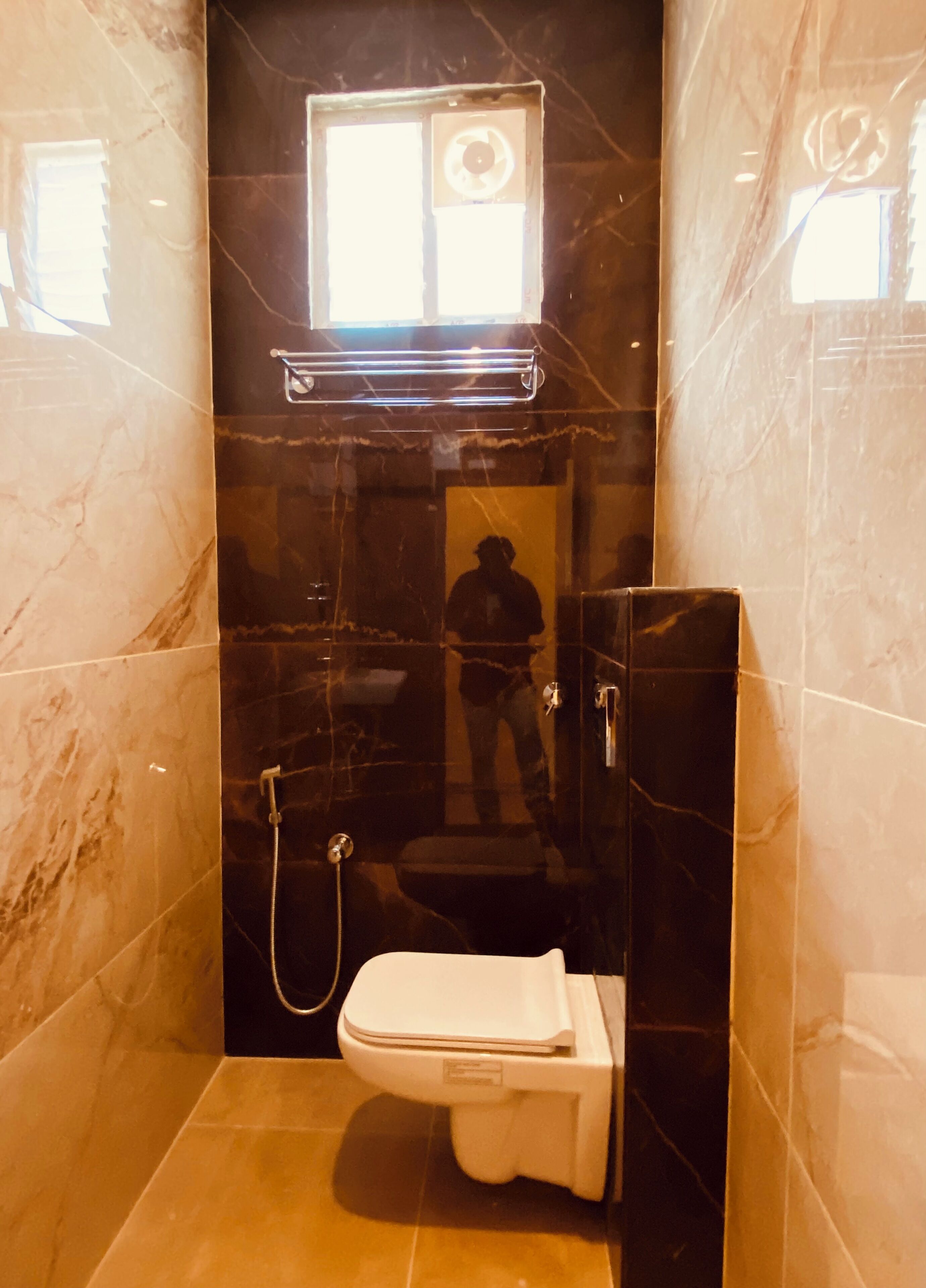 A bathroom with a toilet, a shower, and a window.