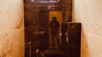 A bathroom with a toilet, a shower, and a window.