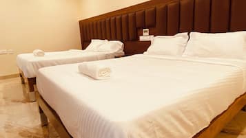 A hotel room with two beds, each with white linens and pillows, and a wooden headboard.
