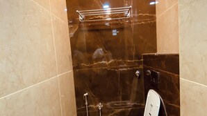 A small, modern bathroom with a toilet, a shower, and a towel rack.