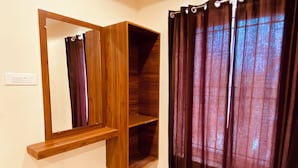 A bathroom with a wooden vanity, a mirror, a shelf, and a shower curtain.
