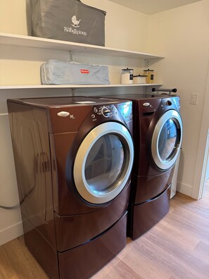 Deux lave-linge Whirlpool Duet de couleur marron, à chargement frontal, sont installés dans une buanderie dont le sol est recouvert de parquet.