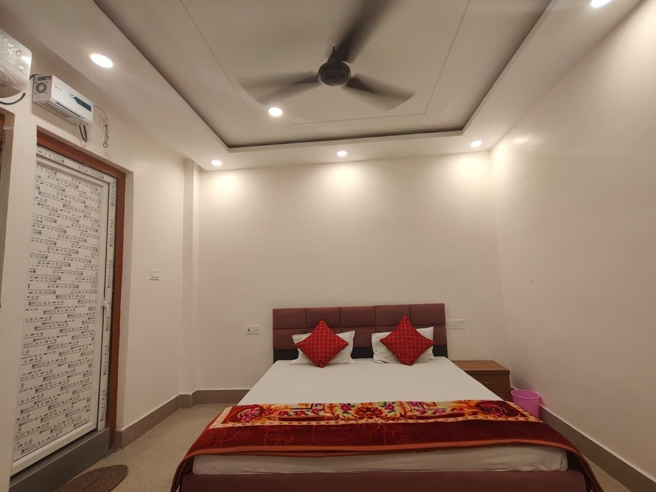 A bedroom with a bed, a ceiling fan, recessed lighting, and a wall-mounted air conditioning unit.