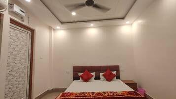 A bedroom with a bed, a ceiling fan, recessed lighting, and a wall-mounted air conditioning unit.