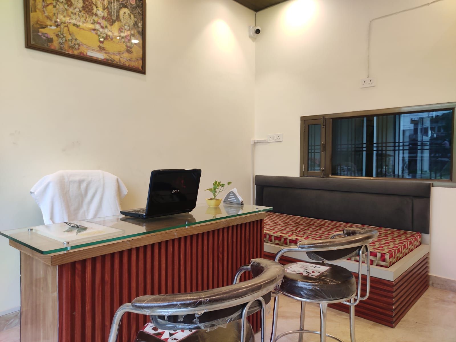 A room with a desk, a laptop, a chair, a sofa, and a window.