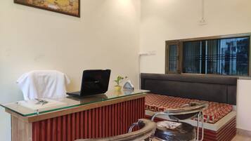 A room with a desk, a laptop, a chair, a sofa, and a window.