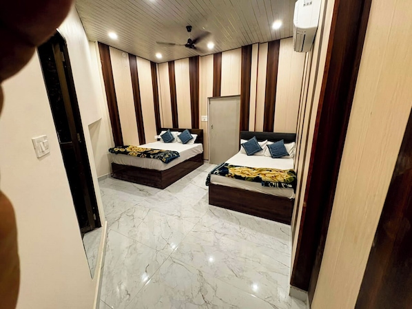 A hotel room with two beds, a ceiling fan, and a whiteboard on the wall. - Shree Shagun Palace (Faizabad)