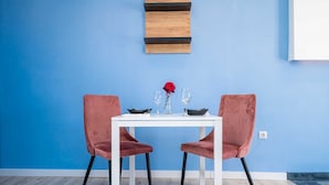 En matplats med ett vitt bord, två rosa stolar och en blå vägg.