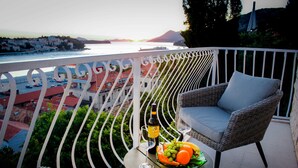 En balkong med en flätstol, ett litet bord med en flaska och glas, och en fruktskål.