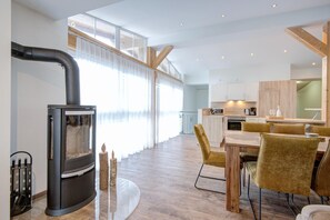 Una cocina moderna con armarios de madera, un comedor con mesa y sillas redondas, y un ventanal con cortinas ligeras.