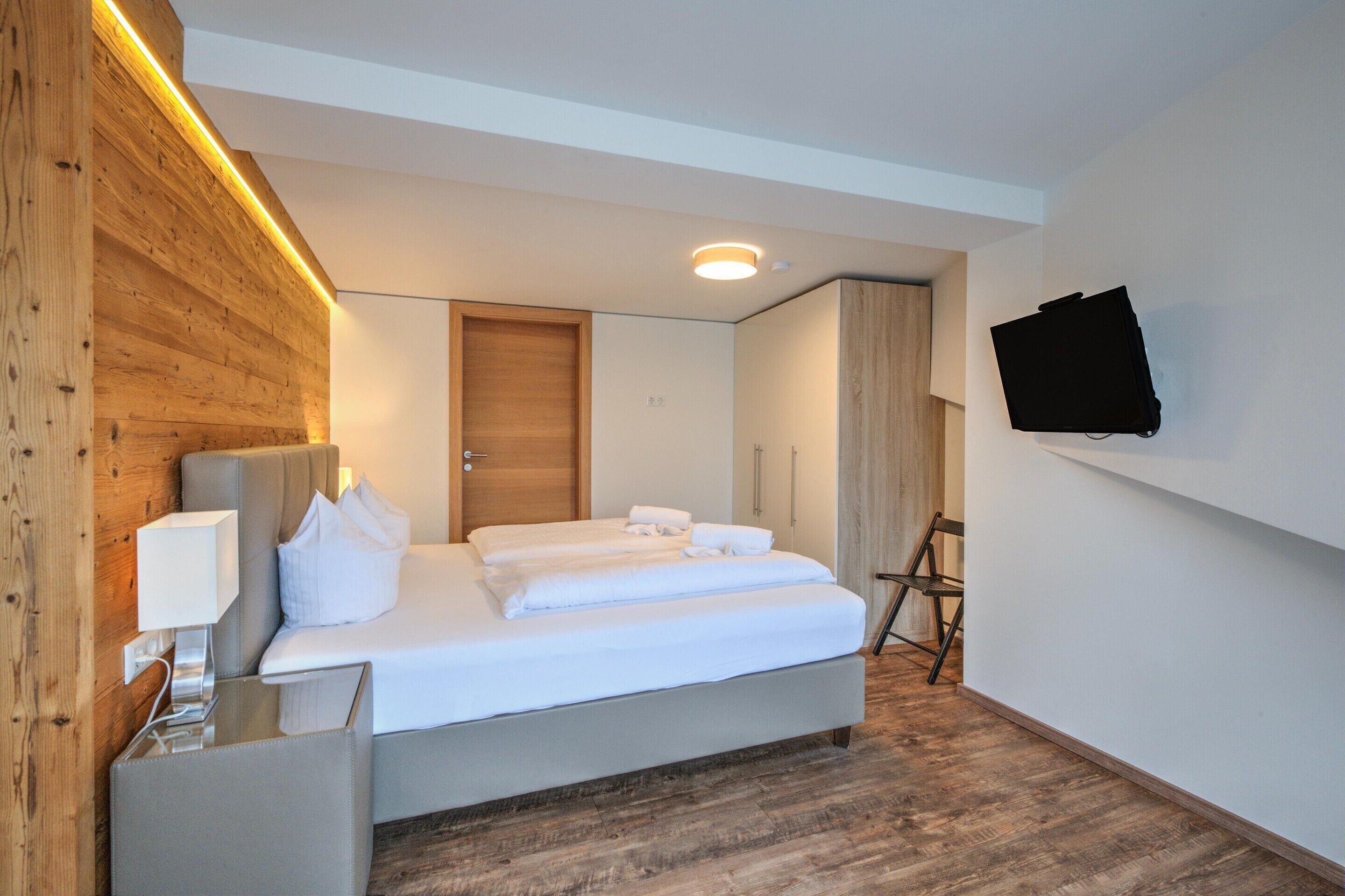 Une chambre d’hôtel moderne, dotée d’un lit, d’un téléviseur à écran plat fixé au mur et d’un mur décoratif en bois.