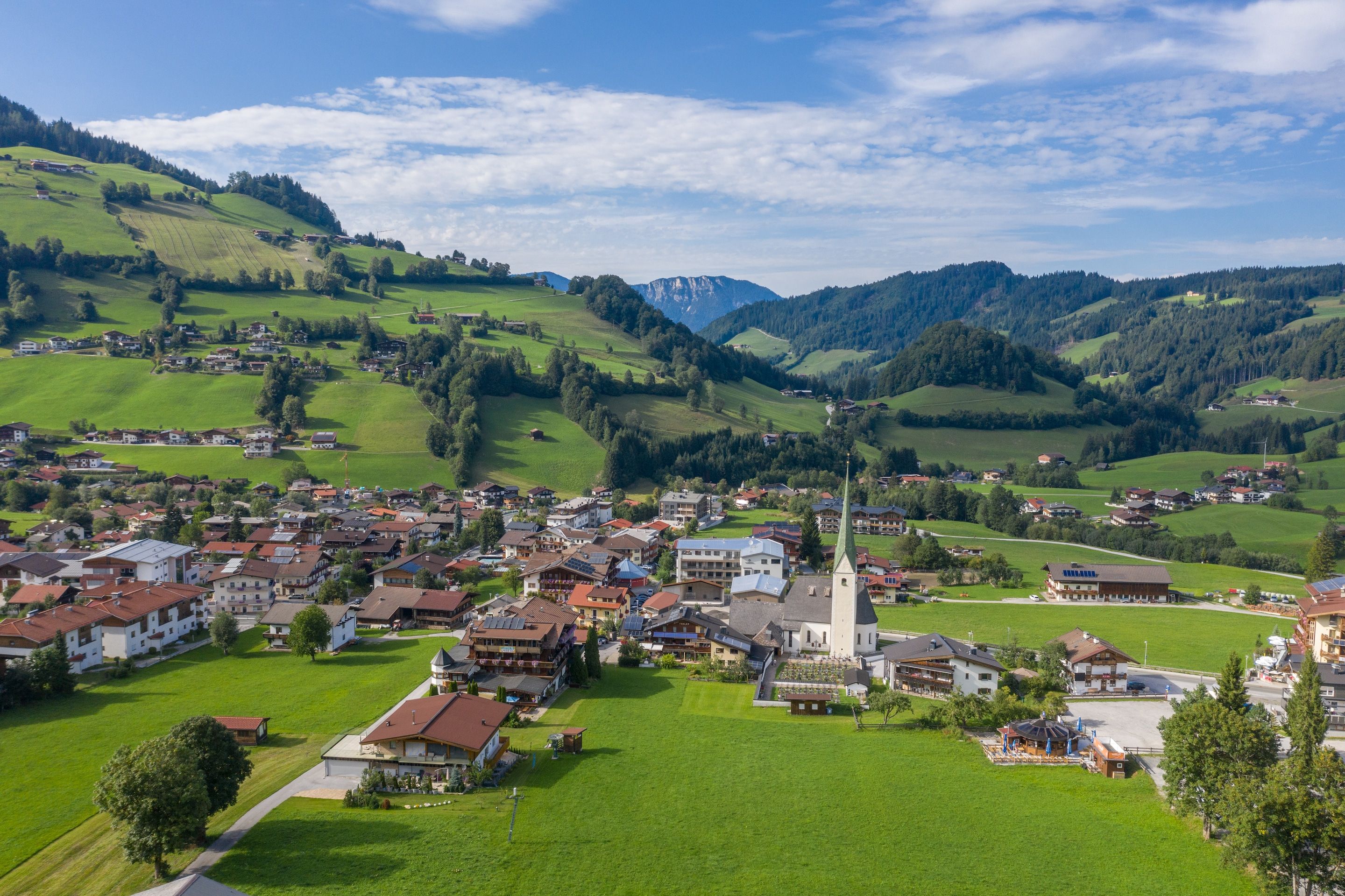 A village with traditional buildings, a church, and a mountain backdrop.