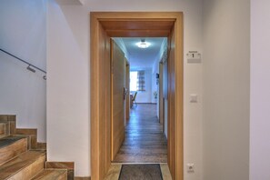 A hallway with a wooden door frame, a staircase on the left, and a sign indicating 'Apartment 1'. - Wildschonau Ski-in Brunner Apartment (Wildschönau)
