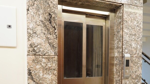An elevator with a metallic finish, set in a building with granite-like walls. - Hotel Rama Continental Second  (Prayagraj)