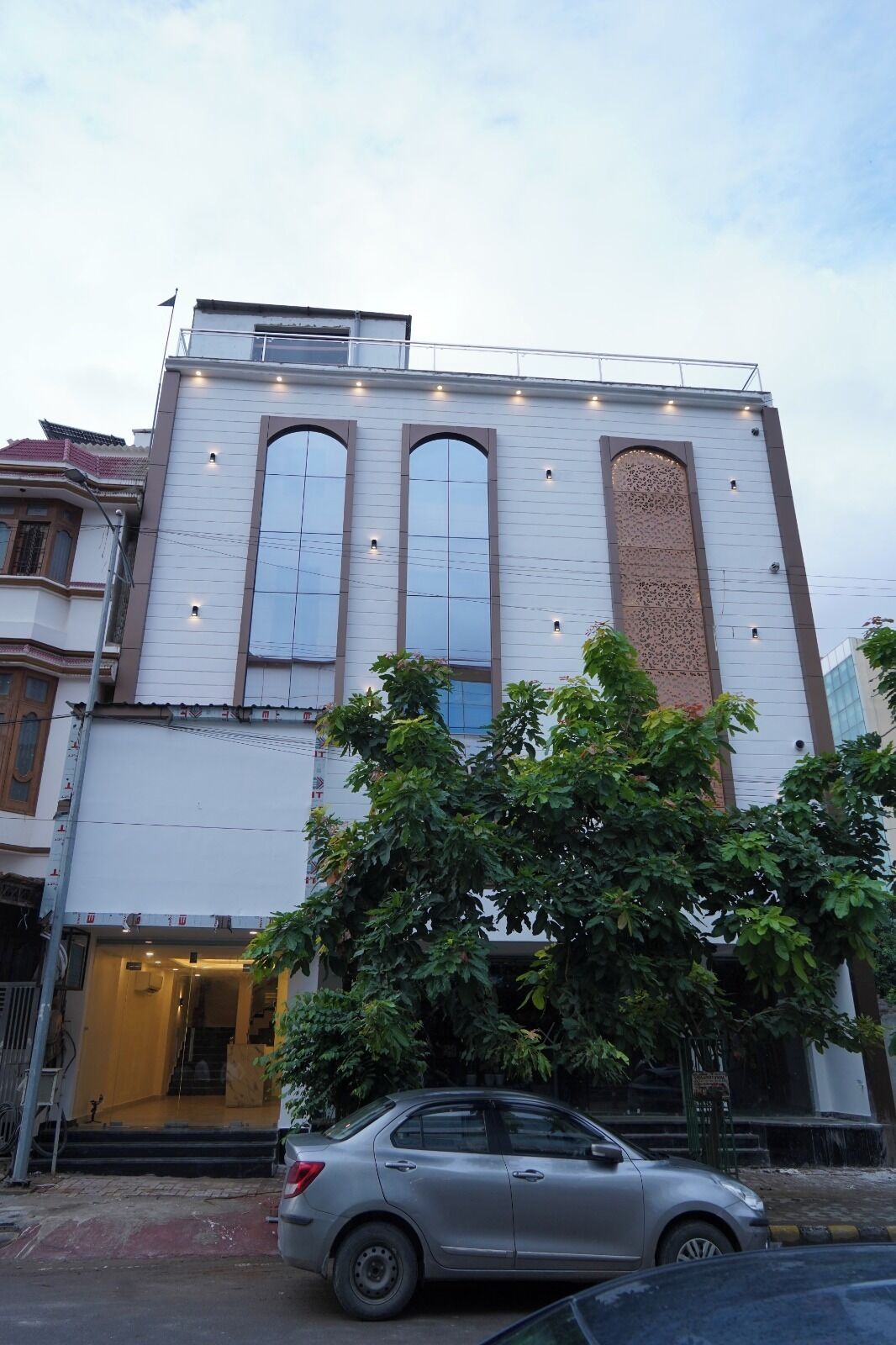 A building with a white facade, large arched windows, and a door with steps leading to the entrance.