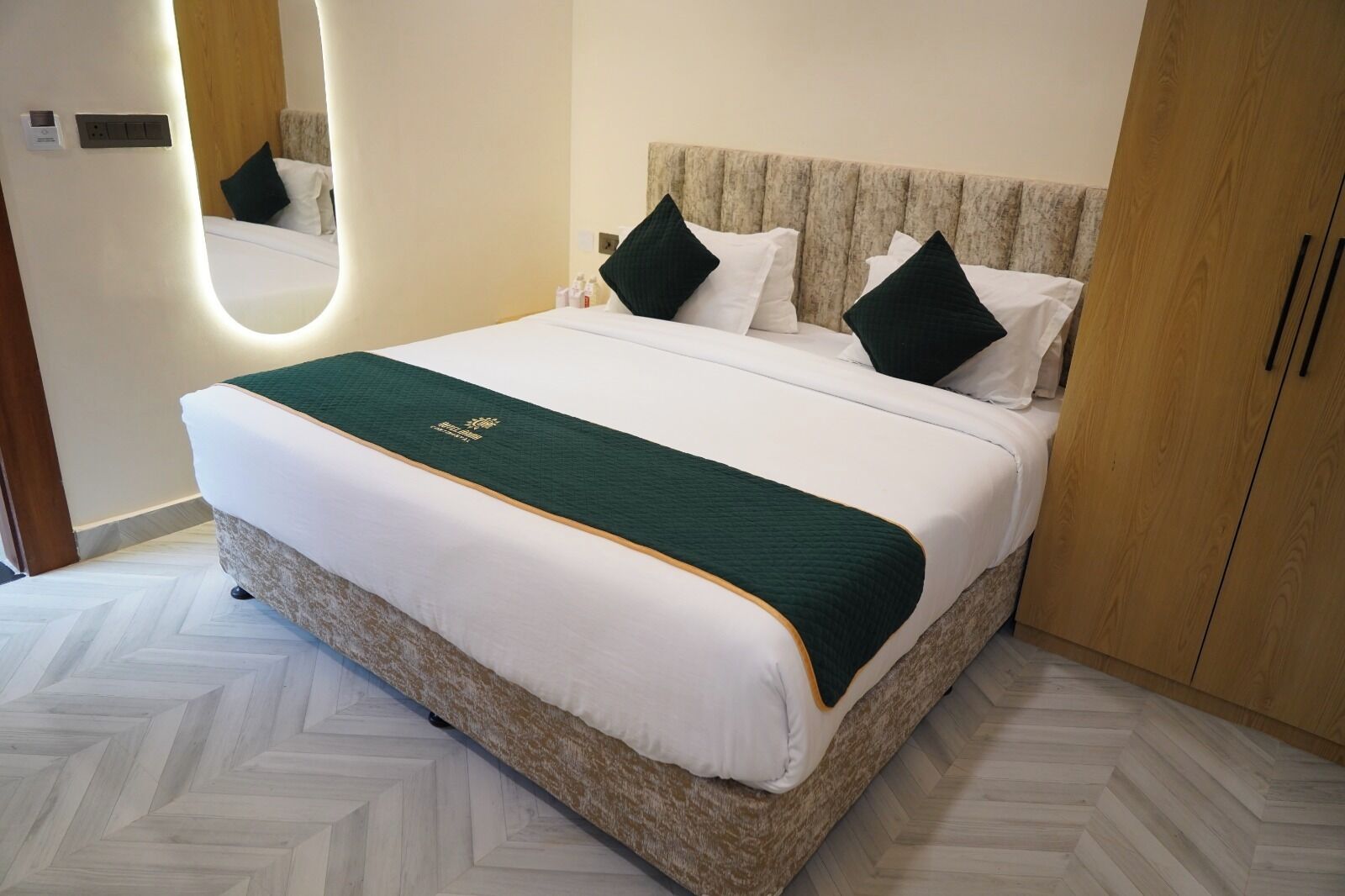A hotel room with a bed, a headboard, a wardrobe, and a mirror.