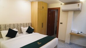 A hotel room with a bed, a wardrobe, a door, and an air conditioning unit. - Hotel Rama Continental Second  (Prayagraj)