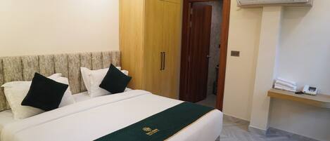 Una habitación de hotel con una cama, un armario, una puerta y un equipo de aire acondicionado.