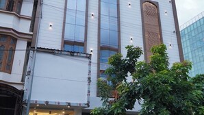 A multi-story building with a white facade, large arched windows, and a visible entrance with steps. - Hotel Rama Continental Second  (Prayagraj)