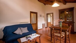 A cozy living room with a blue sofa, wooden dining table, and chairs. - Villa Angelisa Grande: A characteristic and welcoming three-story ancient tuscan country house surrounded by meadows and by green hills, with Free WI-FI. (Castiglion Fiorentino)