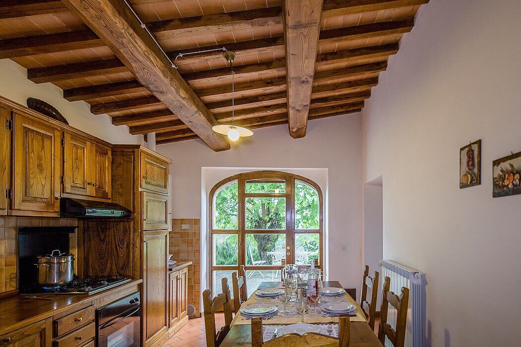 A rustic kitchen with wooden cabinets, a stove, and a dining area with a table set for four.