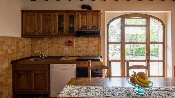 A kitchen with wooden cabinets, a dishwasher, and a window with a view of greenery. - Villa Angelisa Grande: A characteristic and welcoming three-story ancient tuscan country house surrounded by meadows and by green hills, with Free WI-FI. (Castiglion Fiorentino)