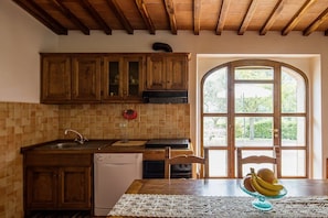 A kitchen with wooden cabinets, a dishwasher, and a window with a view of greenery. - Villa Angelisa Grande: A characteristic and welcoming three-story ancient tuscan country house surrounded by meadows and by green hills, with Free WI-FI. (Castiglion Fiorentino)