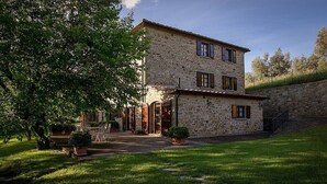 A stone building with a courtyard, featuring a large tree and potted plants. - Villa Angelisa Grande: A characteristic and welcoming three-story ancient tuscan country house surrounded by meadows and by green hills, with Free WI-FI. (Castiglion Fiorentino)